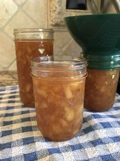 three jars filled with food sitting on top of a blue and white checkered table cloth