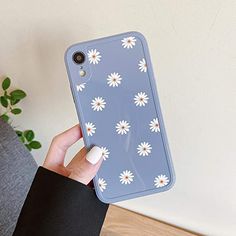 a person holding up a phone case with daisies on it