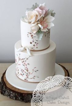 a three tiered white cake with flowers on top and lace doily around the edges