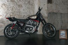 a motorcycle parked in front of a stone wall with exposed pipes and black leather seat