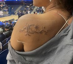 a woman with a tattoo on her shoulder at a basketball game