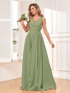 a woman in a long green dress standing on a hard wood floor holding a flower