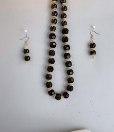 Black round glass beads accented with gold bead caps, comes with matching earrings. Necklace is 11" long, earrings are 1 1/2" long and come with soft gel backs for extra comfort. Jewelry is also glued at ends to give extra protection. Jewelry comes packaged in black jewelry box with soft white pad, and 3" x 5" organza bag. Thanks for shopping at an American Shop. Black Dangling Beads Jewelry For Festive Occasions, Black Jewelry With Dangling Beads For Festive Occasions, Festive Black Jewelry With Dangling Beads, Black Faceted Bead Earrings For Gift, Black Faceted Beads Earrings For Gift, Black Beaded Necklace With Gold Beads As Gift, Black Beaded Necklace With Gold Beads For Party, Elegant Black Jewelry Sets For Festive Occasions, Black Faceted Beads Earrings For Party