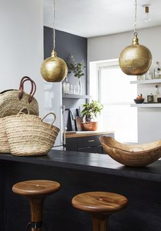 some baskets hanging from the ceiling in a room with two stools and one table