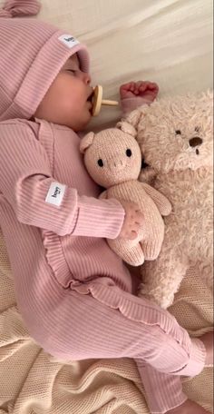 a baby sleeping next to a teddy bear with a pacifier in it's mouth