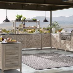 an outdoor kitchen with grill, sink and counter tops on the outside patio overlooking mountains