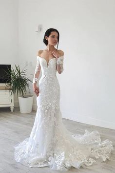 a woman in a white wedding dress posing for the camera with her hands on her hips