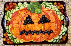 a platter filled with veggies and fruit in the shape of a pumpkin