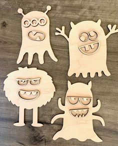 three wooden cut outs with faces and eyes, one in the shape of two monsters