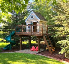 there is a small wooden house with a slide in the yard and trees around it