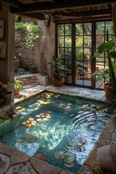 an indoor swimming pool with water lilies and plants in the center, surrounded by stone walls