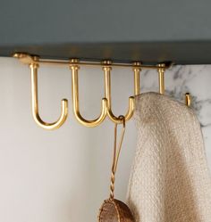 a towel hanging on a rack next to a white and gray wall with gold hooks