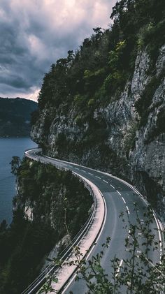 a winding road on the side of a mountain with water below metal print by panoramic images