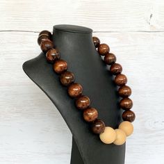 This chunky wood necklace was hand beaded using a mix of large 25mm round dark brown and 28mm round medium tone tan wooden beads in a modern color block design. The necklace measures 24 inches long and is securely fastened with a silver clasp.  Perfect for any gender!  Length can be adjusted if needed - just ask! Wood represents a sense of earthiness, spirituality, creativity, liberty, prosperity, health, and natural touch.  Perfect for meditation, prayer, yoga practices, and everyday wear!    C Handmade Brown Round Beaded Necklaces, Handmade Brown Beaded Necklaces, Earthy Brown Round Necklace, Artisan Brown Round Necklace, Earthy Brown Necklace With Large Beads, Rustic Brown Wooden Bead Necklaces, Brown Round Beaded Necklace With Large Beads, Brown Beaded Necklace With Large Round Beads, Rustic Brown Wooden Beaded Necklaces