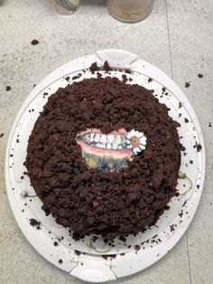 a chocolate cake sitting on top of a white plate covered in crumbled dirt