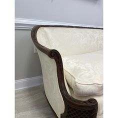 a white and brown couch sitting on top of a hard wood floor next to a wall