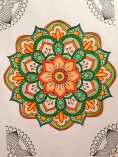 a drawing of an orange and green flower on white paper with paisley designs in the background