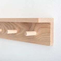 three toothbrushes are mounted on a wooden shelf against a white wall with wood trim