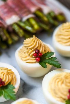 deviled eggs with whipped cream and holly on top, surrounded by other deviled eggs