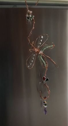 a spider is hanging from a wire with beads on it's back and wings