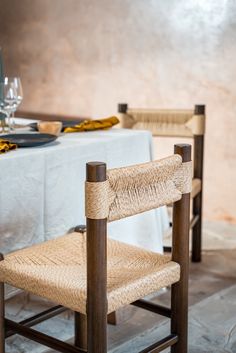 two chairs sitting at a table with a white table cloth and place settings on it