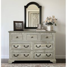 an old dresser with flowers and a mirror on top