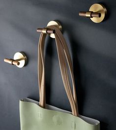 a bag hanging on the wall next to two hooks and a handbag with handles