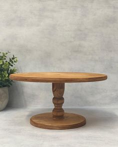 a wooden table sitting next to a potted plant on top of a white floor