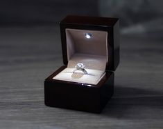 an engagement ring in a wooden box on a table