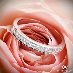 two wedding rings sitting on top of a pink rose with diamonds in the middle and bottom