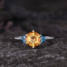 an orange and blue diamond ring sitting on top of a rock