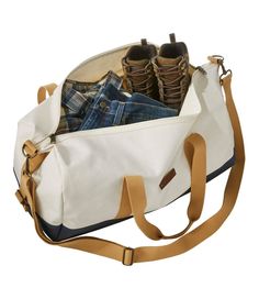 a white canvas bag filled with pairs of shoes and jeans sitting on top of it