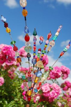 there are many colorful beads on the top of this pole in front of pink flowers