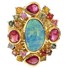 Bochic "Orient” Opal, Ruby & Multi Sapphire Vintage Cluster Ring Set 18K & Silver Center Blue Opal - 2 Carat Ruby natural - 4 Carats Blue natural sapphire Pink natural sapphire Yellow natural sapphire Orange natural sapphire Green natural emeralds Gray natural gray single cut diamonds 5 carats This Ring is from the "Orient" traveling collection are the epitome of elegance and versatility. It offers a perfect blend of day to night and swimwear to evening wear, allowing you to effortlessly transit Vintage Cluster Ring, Cluster Ring Set, Sapphire Cocktail Ring, Multi Sapphire, Gold Cocktail Ring, Gold Cocktail, Ruby Sapphire, Garnet Rings, Natural Sapphire