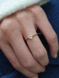 a woman's hand wearing a gold ring with two diamonds on the middle finger