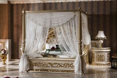 a fancy bed with white drapes and gold trimmings in a luxurious bedroom