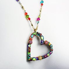 This heart hoop necklace embellished with a wide variety of multi-color Swarovski crystal and glass beads set into rainbow enamel placed on a chain beaded with Swarovski crystals and glass beads is inspired by it's own abstract and bright shape. This handmade piece is a one of a kind, fashionable statement necklace that will be perfect for any spring outfit or as a lovely gift for valentine's day.Pendant Length: 1.75 inchesPendant Width: 1.5 inchesNecklace Length: 20.25 inchesAdditional Extender Multicolor Beaded Heart Pendant Necklace, Heart Shaped Metal Jewelry With Beaded Chain, Heart-shaped Metal Beaded Chain Jewelry, Heart Pendant Jewelry With Colorful Beads For Gift, Valentine's Day Colorful Beads For Jewelry Making, Multicolor Jeweled Necklaces With Round Beads, Multicolor Heart-shaped Beaded Chain Necklace, Unique Multicolor Enamel Necklaces, Unique Multicolor Enamel Necklace