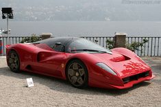 a red sports car parked next to a lake