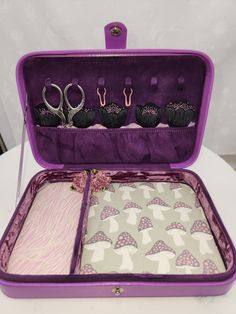 an open purple suitcase filled with pairs of scissors on top of a white tablecloth