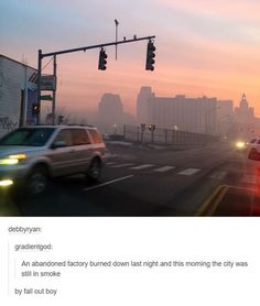 an image of cars driving down the road at sunset or sunrise with buildings in the background