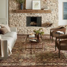 a living room filled with furniture and a fire place in front of a stone wall