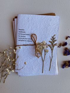 some dried flowers are tied up and sitting next to two envelopes that have writing on them