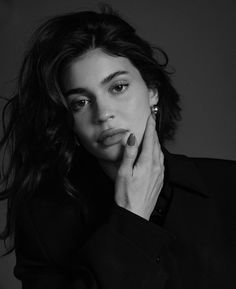 a black and white photo of a woman with her hand on her chin looking at the camera