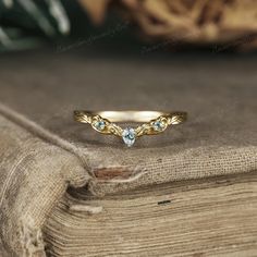 a gold ring with three diamonds on top of a wooden table next to a book