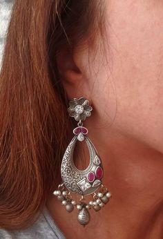 Stunning German silver Indian Chandbali earrings, embellished with sparkly cut CZ stones. Eye catching asymmetric design with a scrolling floral pattern on one half of the earring, and the CZ stones on the other half! Beautiful dangly pearls and silver color stamped balls move when you move, in a very alluring way! Pretty ear stud in shape of flower. Grey finish, polished to a lovely soft lustre. Lots of intricate detail! Excellent quality and craftsmanship! Length 3 3/4 in Width 2 in Weight 14 Silver Pearl Earrings With Stone Work For Gift, Silver Chandbali Fusion Jewelry, Silver Meenakari Chandelier Earrings For Festivals, Silver Pearl Earrings With Stone Work For Celebration, Silver Fusion Bridal Earrings With Intricate Design, Silver Kundan Pearl Earrings With Stone Work, Silver Meenakari Chandelier Earrings For Diwali, Silver Bollywood Hoop Earrings With Intricate Design, Silver Traditional Pearl Earrings With Stone Work