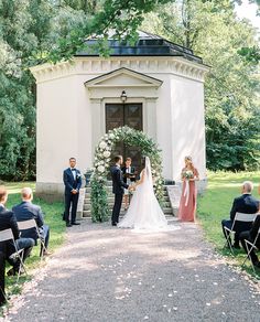 a bride and groom are getting married in front of an old building with greenery