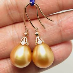 "Lovely in house designed dangle earrings, made of 14k solid yellow gold with 14 natural mine small accent diamonds & a natural GOLDEN, south sea cultured pearls from Australia. Each of the large 'Find Drop' pearl exhibits excellent high luster and thicker nacre. The pearls also possesses a silky smooth surface with just a minimal natural spots/blemish. Style: Hook. Metal Purity: 14k Solid Yellow Gold. Genuine Diamond: 14 pcs / 0.059 ctw. Earring approx. Length (including pearl): 1.4 inches South Sea Pearls Earrings, Akoya Pearl Earrings, Wear Pearls, Golden South Sea Pearls, Sea Pearls, Pearl Types, South Sea Pearls, Yellow Gold Earring, Cultured Pearls