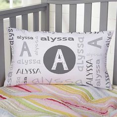 a bed with a pillow that has the letter a on it and is next to a crib