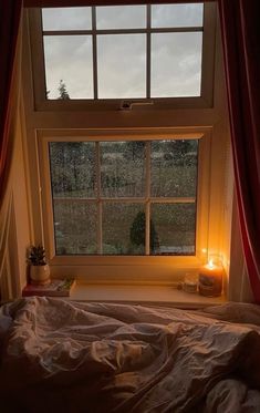 a bedroom with a bed and a window that is lit up by candles on the windowsill