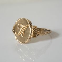 a gold signet ring with the letter f on it's center and an initial in the middle